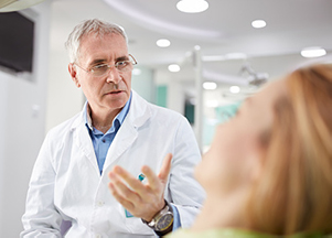 Dentist speaking to patient in dental chair about caring for dental veneers at Premier Dental Center.