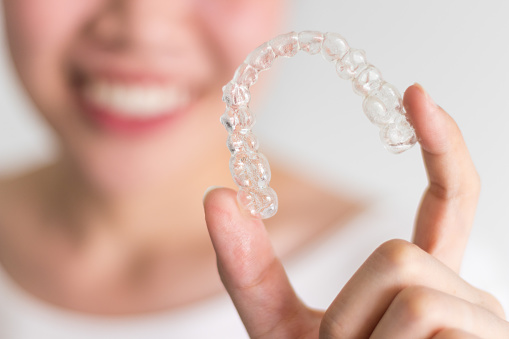 Woman holding clear aligner tray at Premier Dental Center.