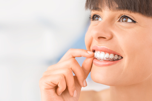 A smiling woman wearing Invisalign at Premier Dental.