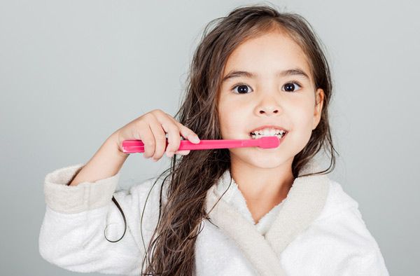 Young girl brushing her teeth at Premier Dental Center.