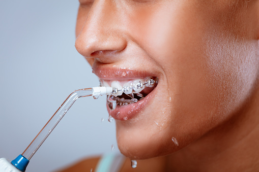 young patient with braces using a water flosser to clean teeth